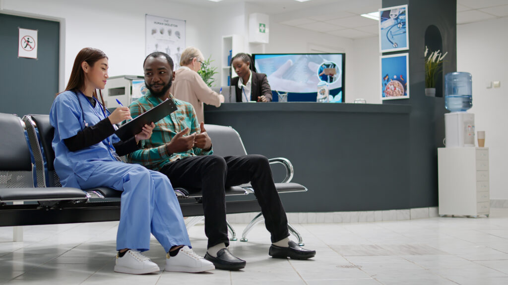 A doctor and her patient sitting beside each other and discussing something at a doctor's office.