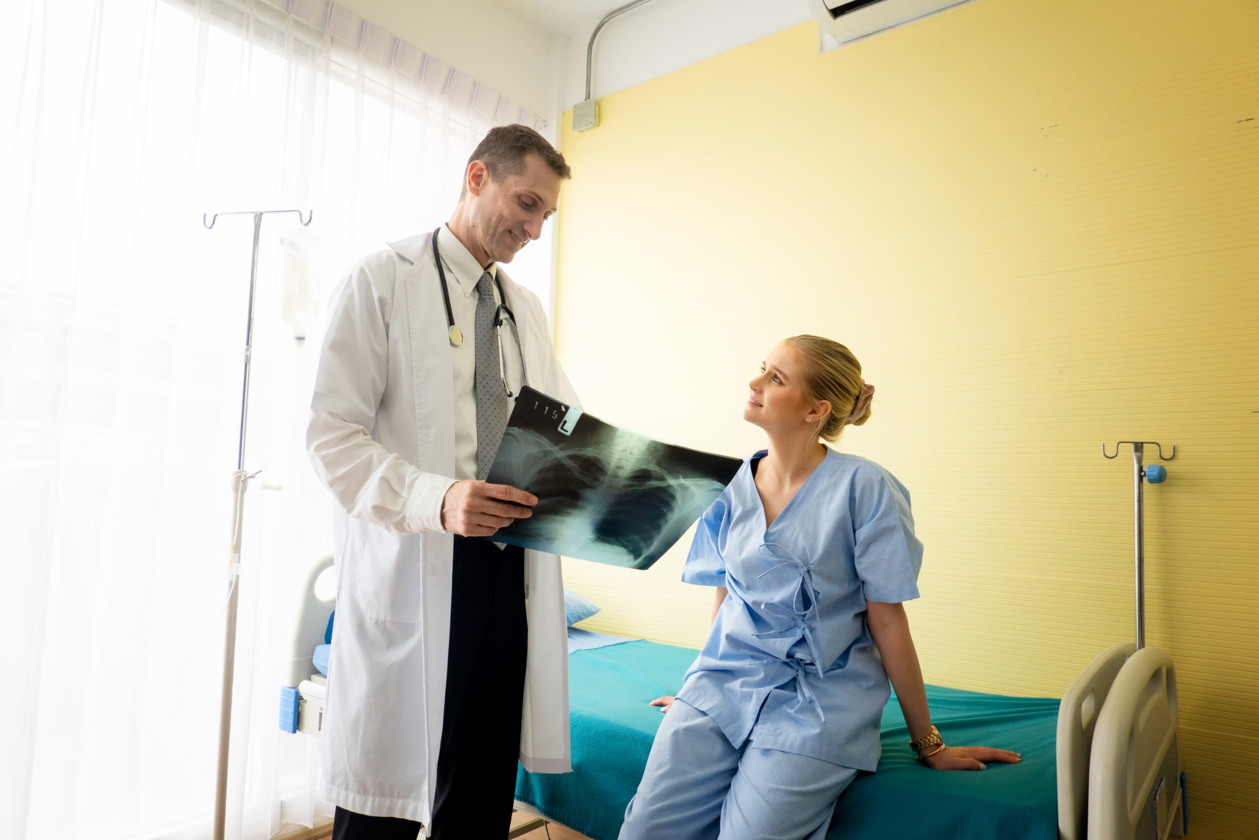 Doctor explaining lungs x-ray to women patient in clinic or Doctor in the office examining an x-ray and discussing with a patient