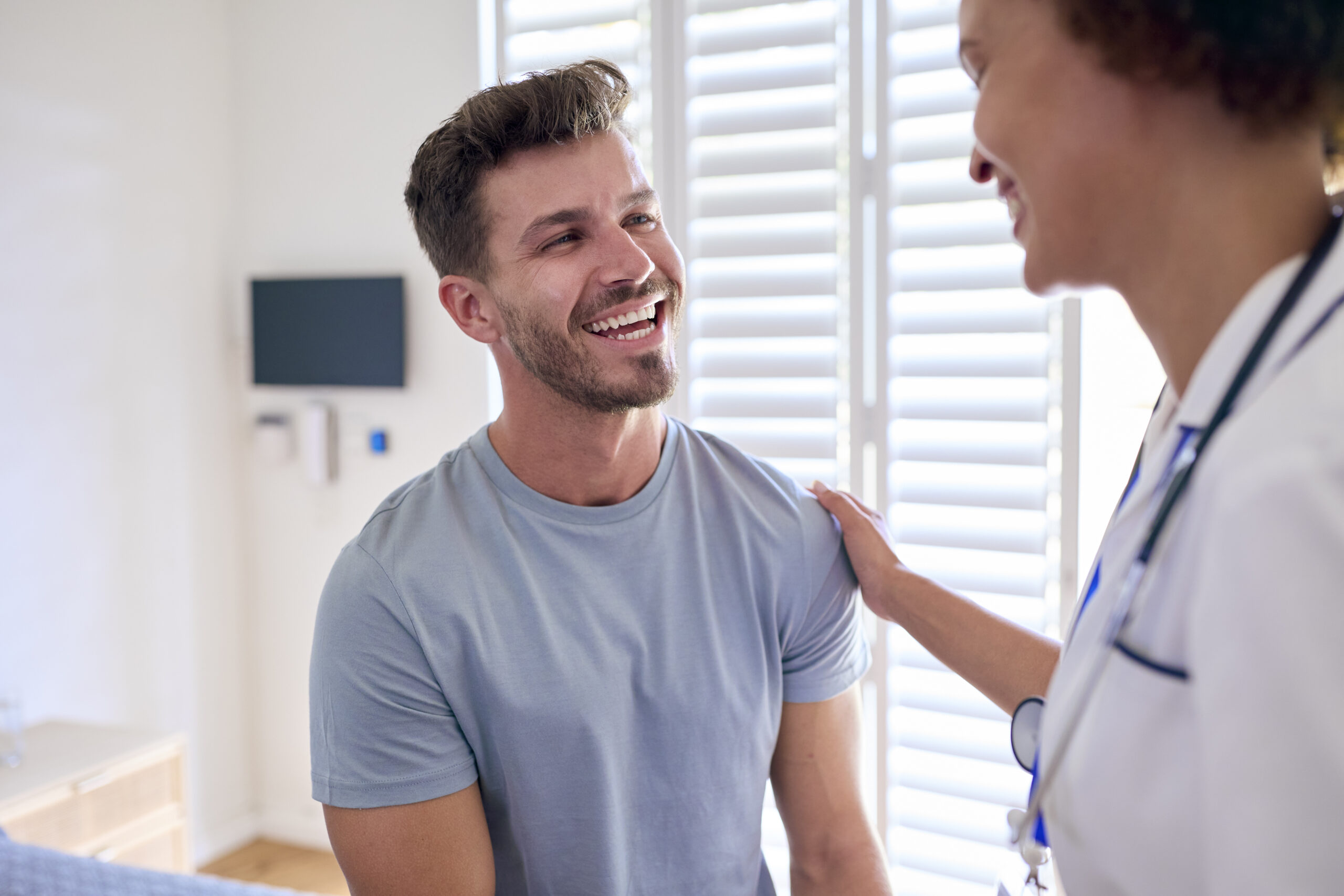 Female Nurse Wearing Uniform Meeting With Male Patient In Private Hospital Room