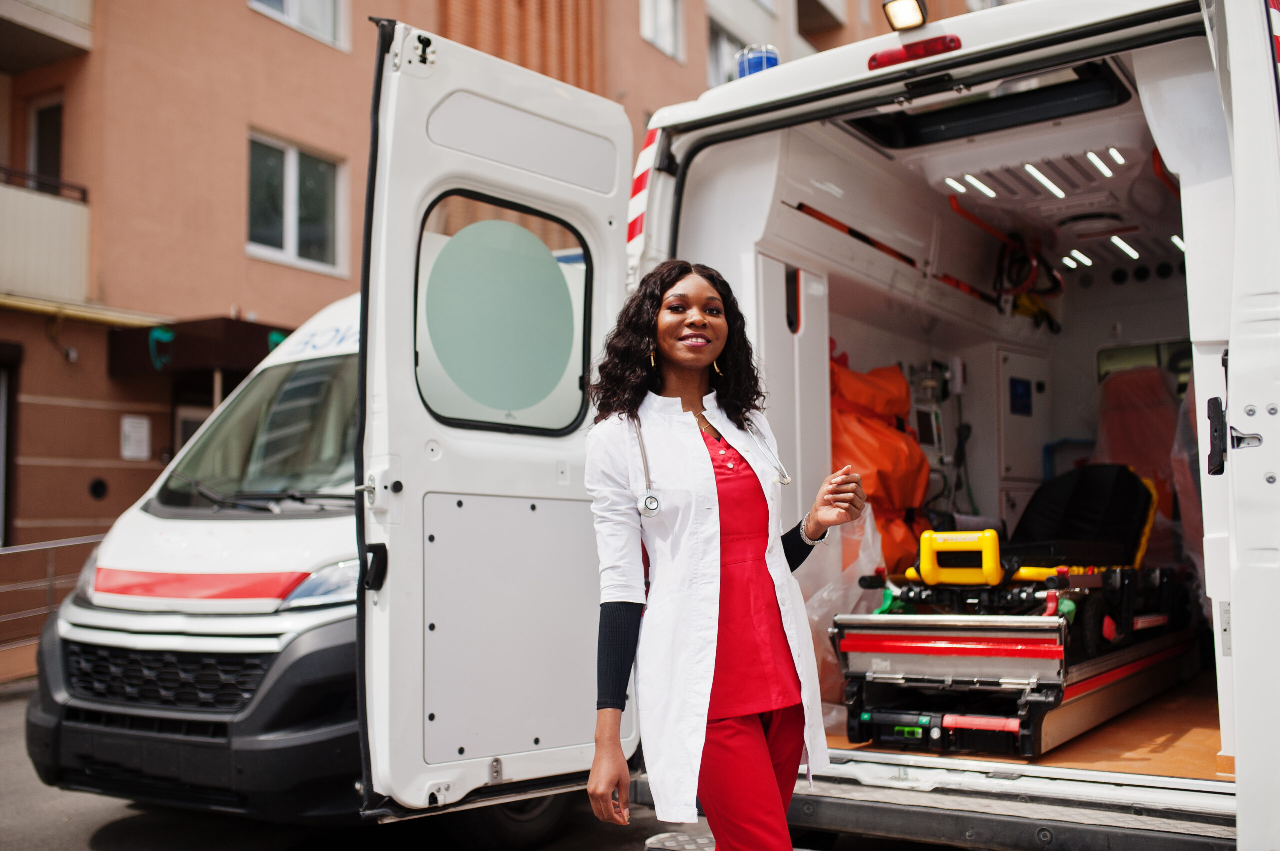 African american female paramedic standing in front of ambulance car.